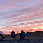 Us sitting in our camper charis outside the campervan admiring the 3 am sunrise in Iceland.
