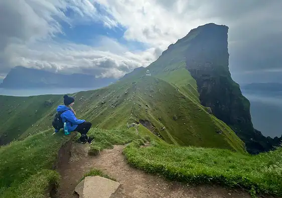 Me sitting along the Kallur lighthouse hike with dramatic cliff views in the background.