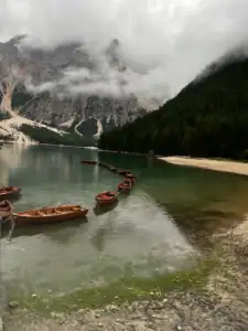 Lago di Braies wooden boats all lined up with the mist covering the top of the mountains in the background.